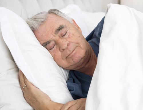 Älterer Mann schläft in seinem Bett